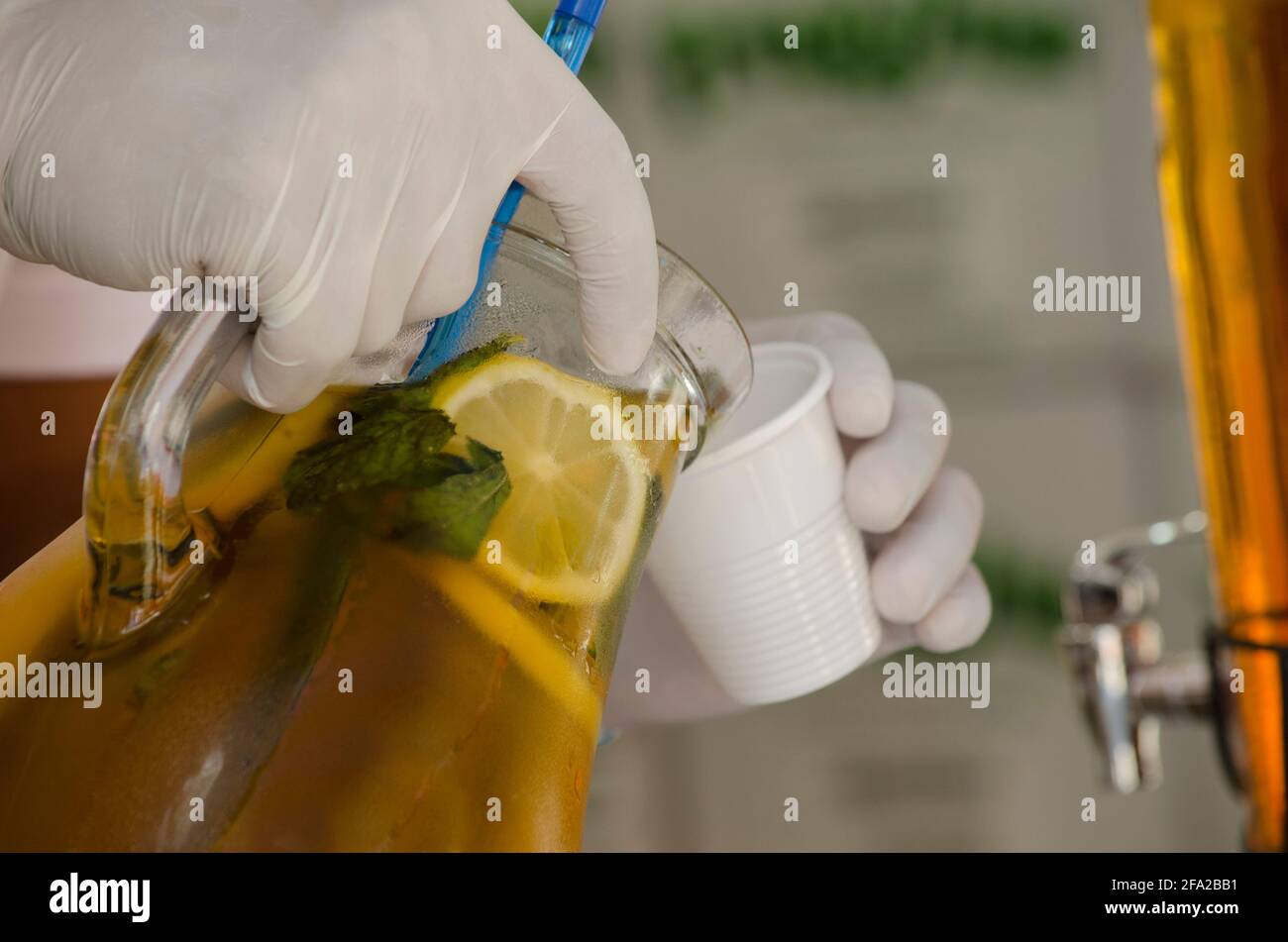 serving juice in a jug with latex gloves, following health protocols