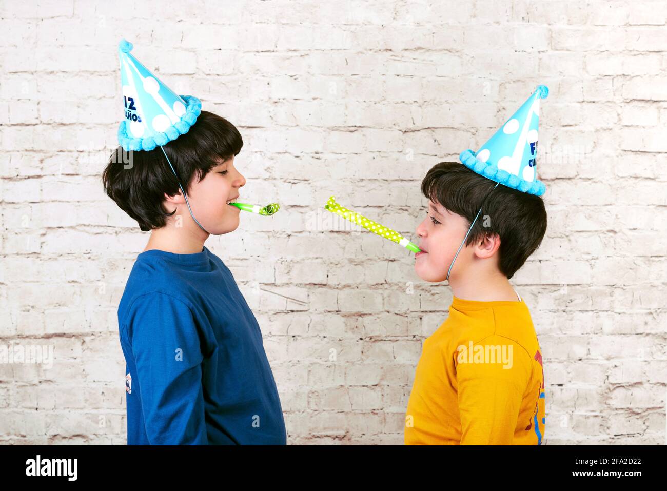 funny kids with party hat blowing in a party horn on white brick wall  background Stock Photo - Alamy