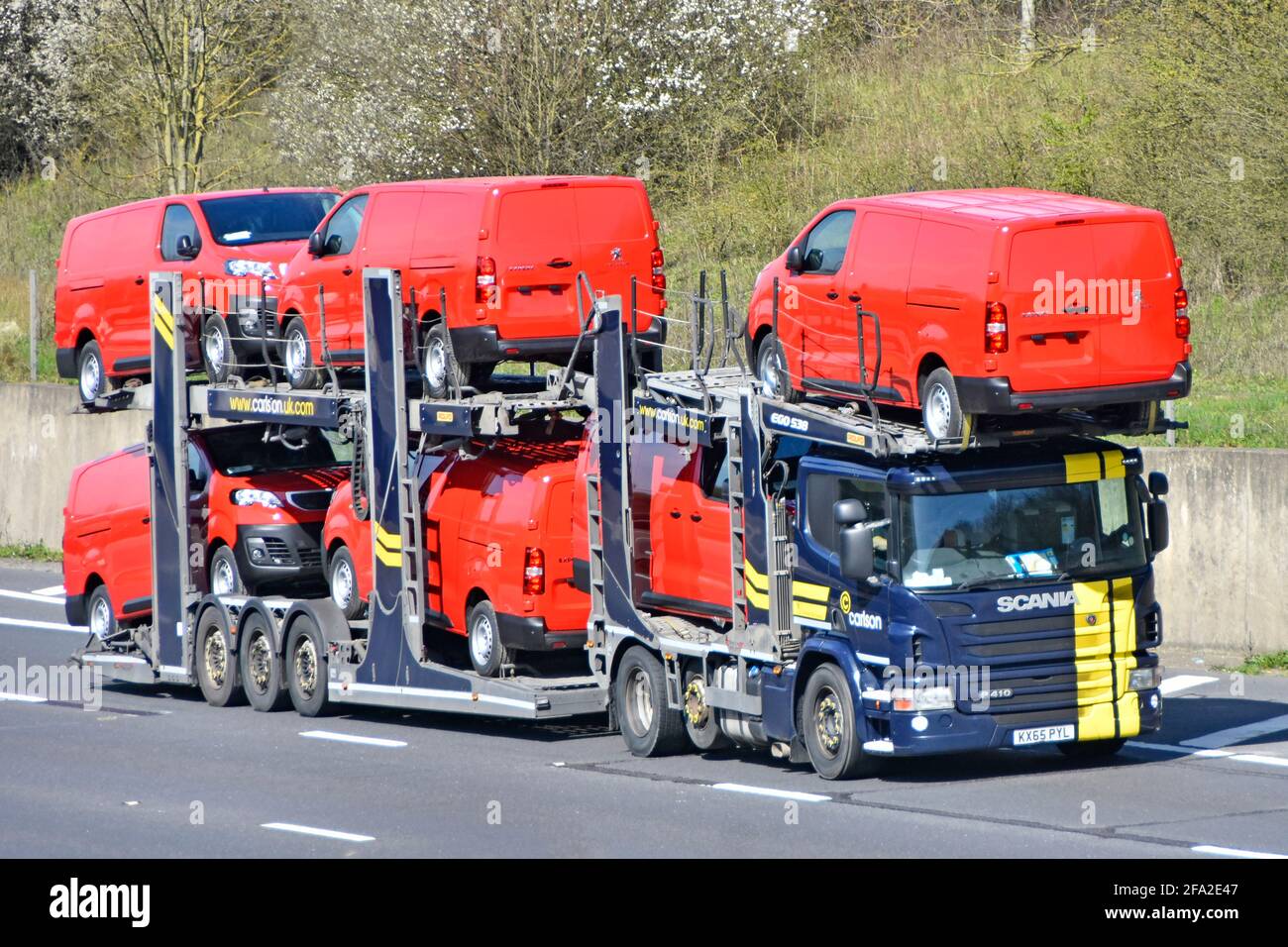 Loaded lorry truck car distribution transporter trailer to transport & deliver six new red Peugeot Expert brand of vans driving on motorway England UK Stock Photo