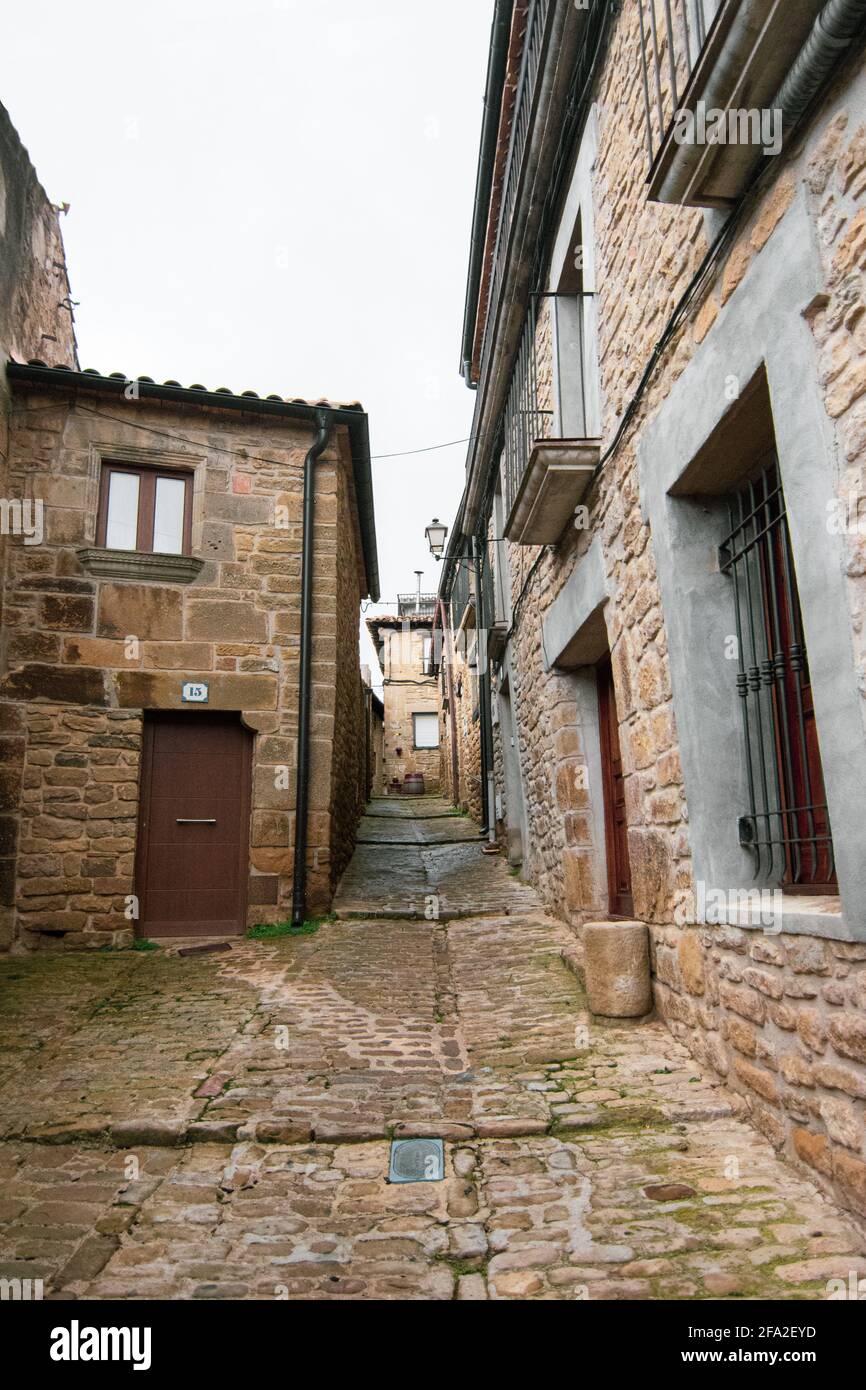 Vertical shot of an alley of old buildings under a cloudy sky in Ujue, Spain Stock Photo