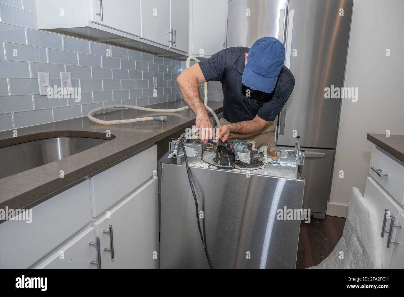 Appliance repairman working on a dishwasher installing the water hoses