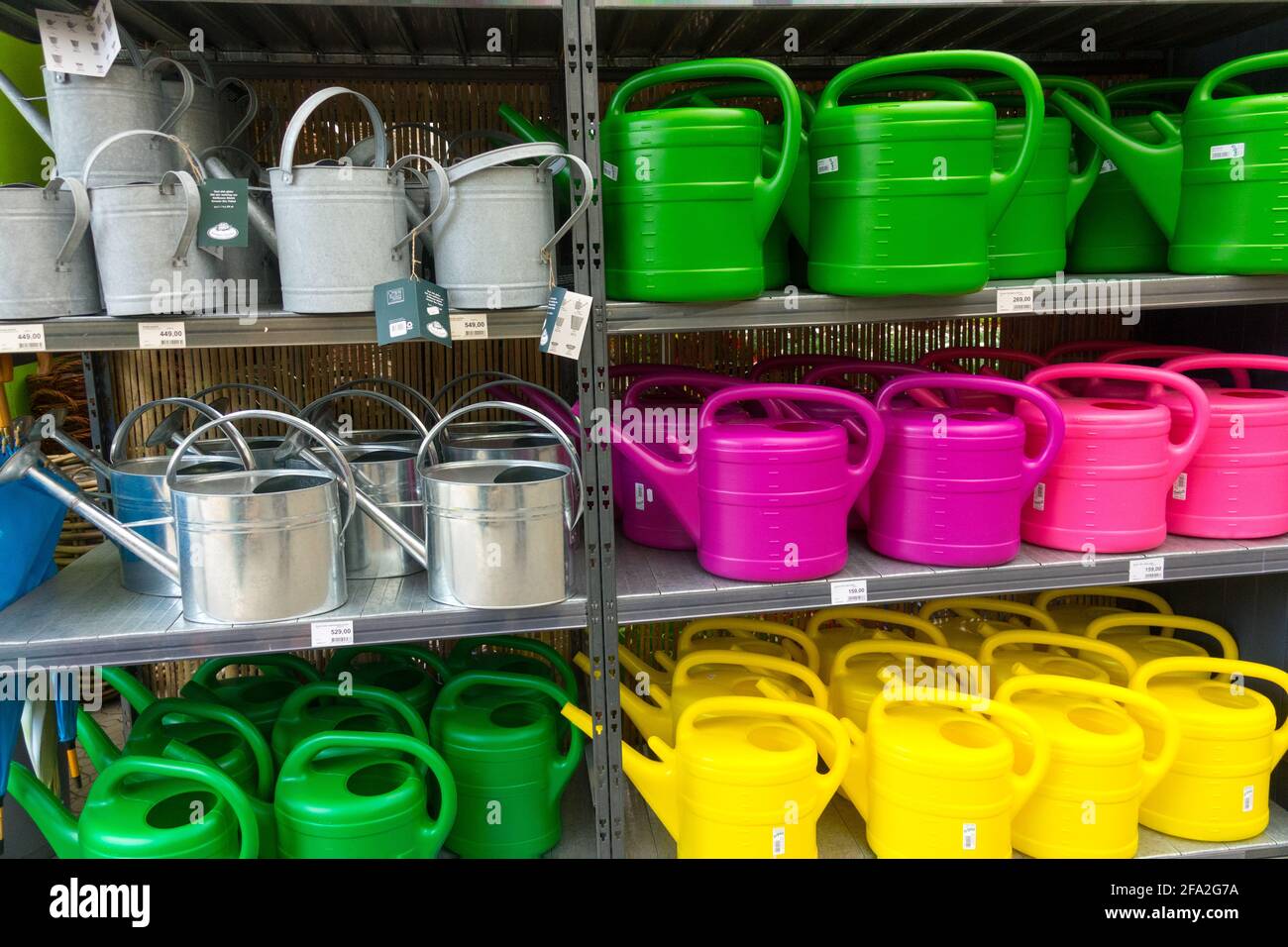 Watering cans for sale in shelves of garden centre Stock Photo