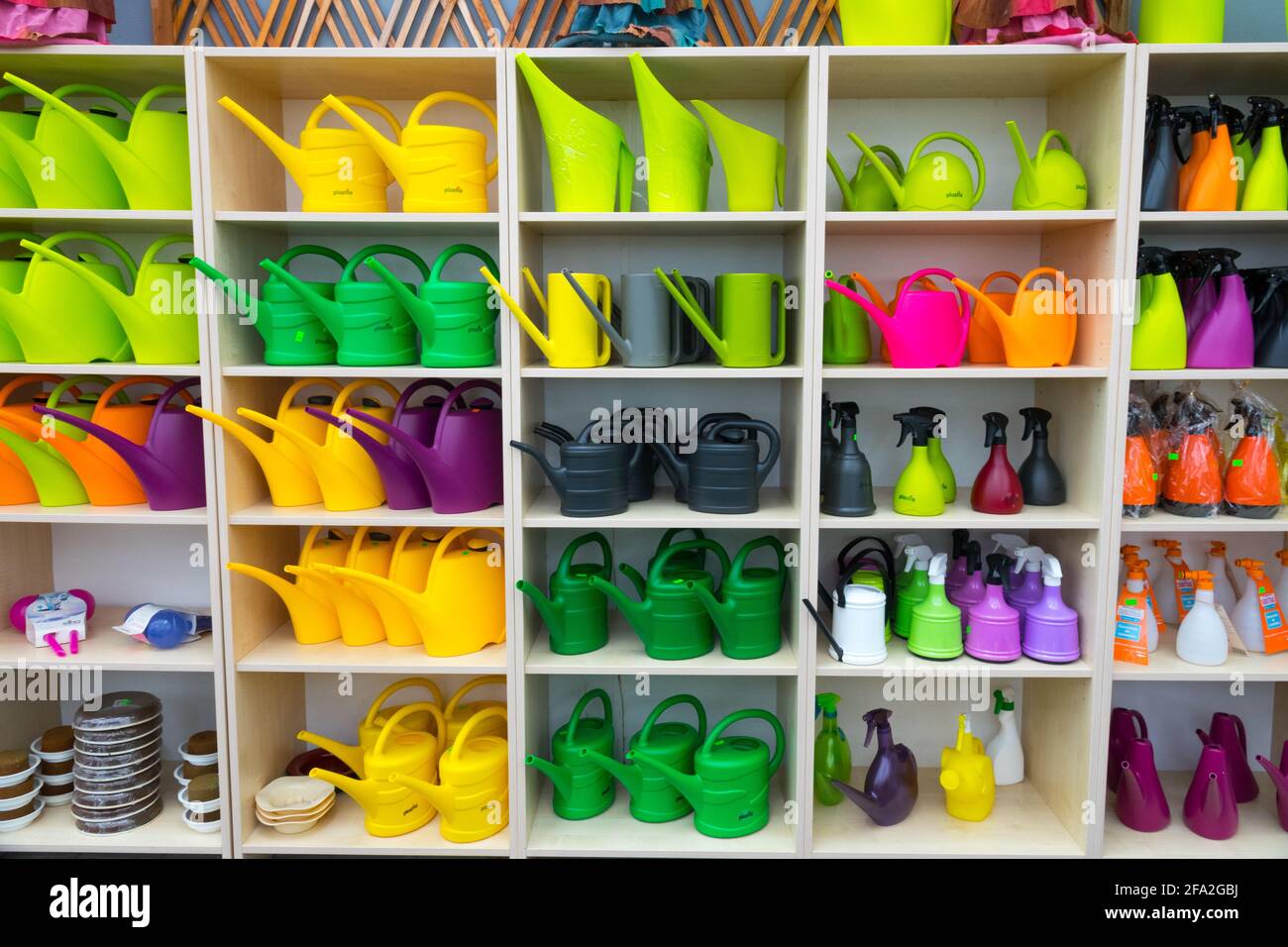 Colorful watering cans on display in shelves, garden centre Stock Photo