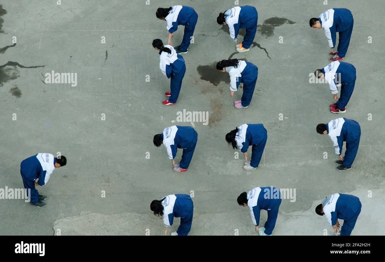 Han Chinese students of the No 11 Middle School in their blue and white school uniforms are doing sport exercises in the compound of their Highschool in the Tianshan district of Urumuqi, Xinjiang, China, PRC. © Time-Snaps Stock Photo