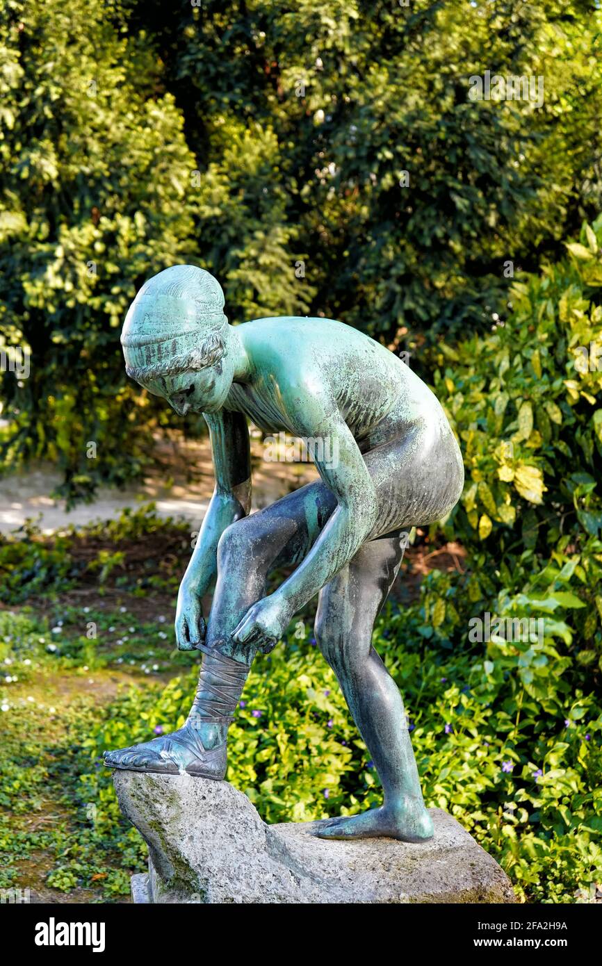 'Sandalenbinderin' (English: girl tying her sandal), a bronze sculpture by the sculptor August Kraus. It was completed in 1901. Stock Photo