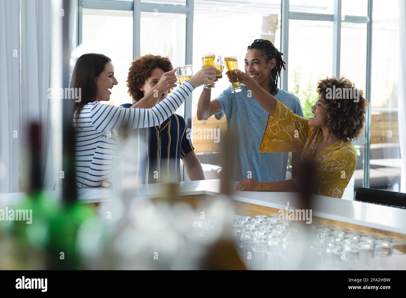 Diverse group of male and female colleagues raising glasses of beer at bar Stock Photo