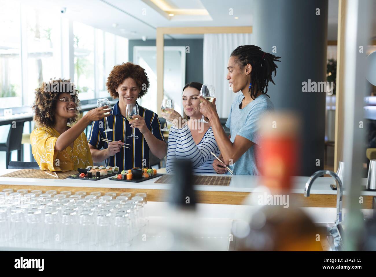 Diverse group of male and female colleagues raising glasses of wine at bar Stock Photo