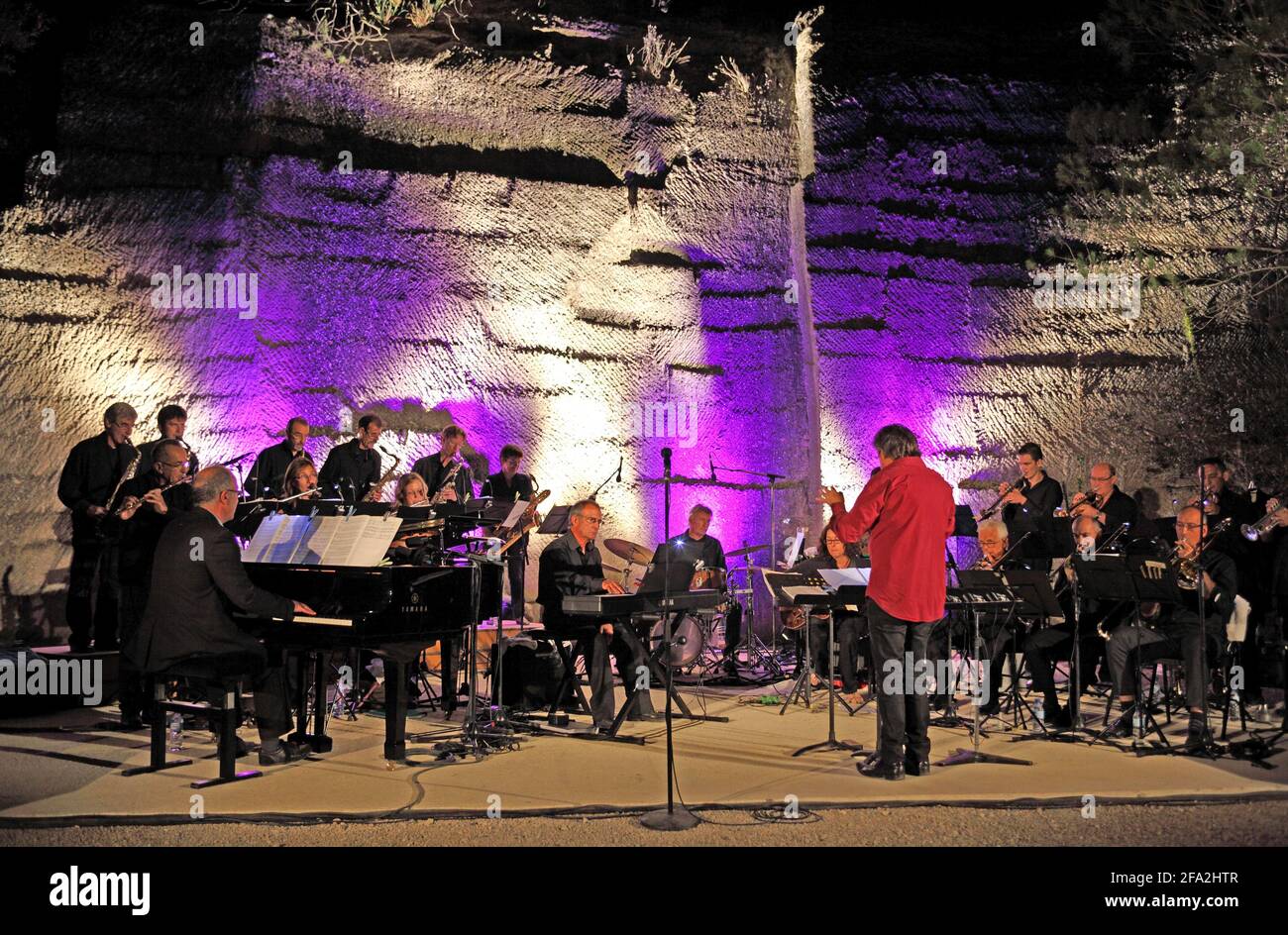 A conductor and Jazz orchestra on stage in the open air Carrieres du Bon Temps, Junas Quarries, Gard, France Stock Photo