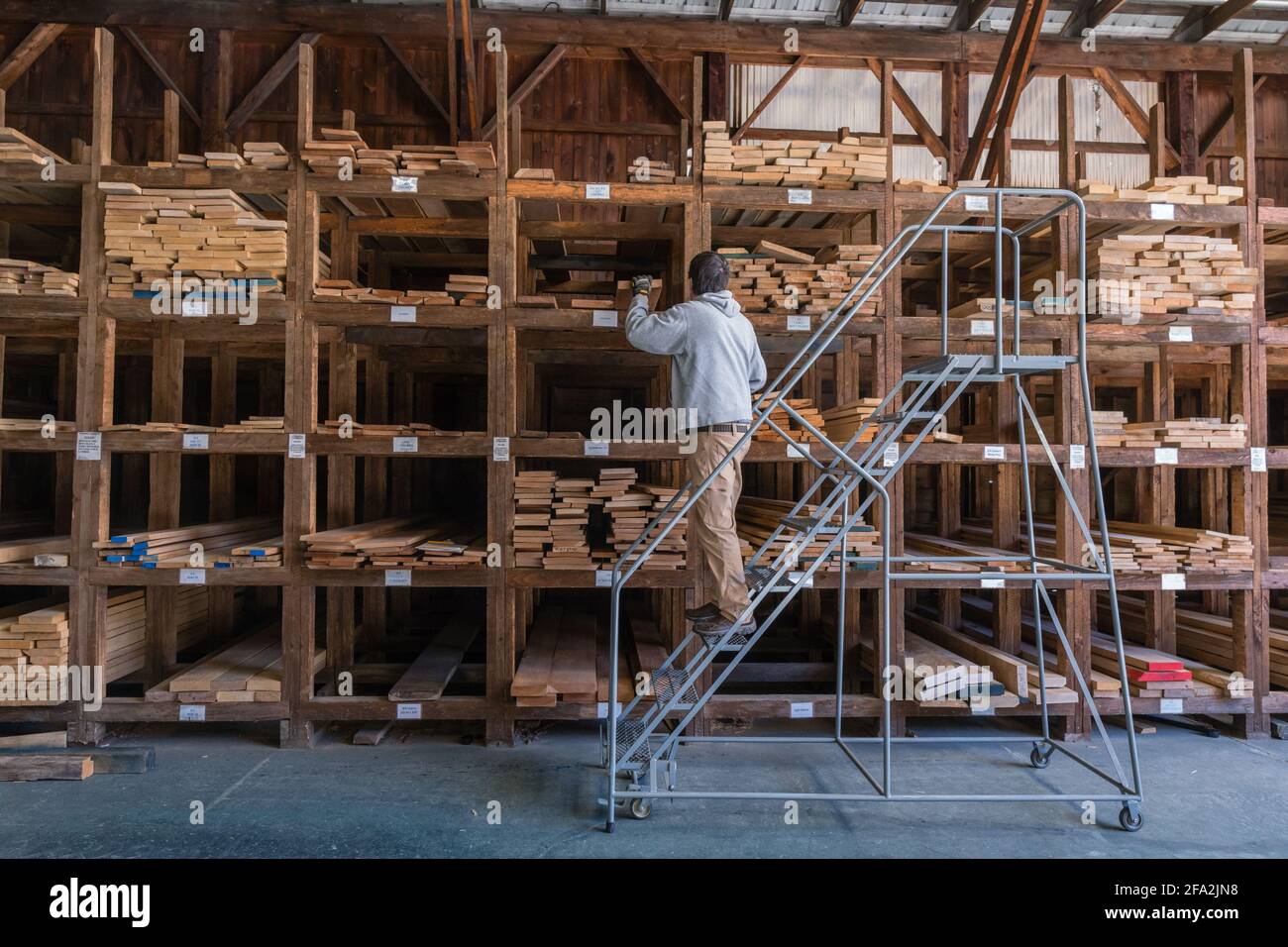 Kingston, NH, US-March 12, 2021: Man choosing wood among stacks of lumber on a rack for sale to consumers at a retail hardwood lumber business Stock Photo