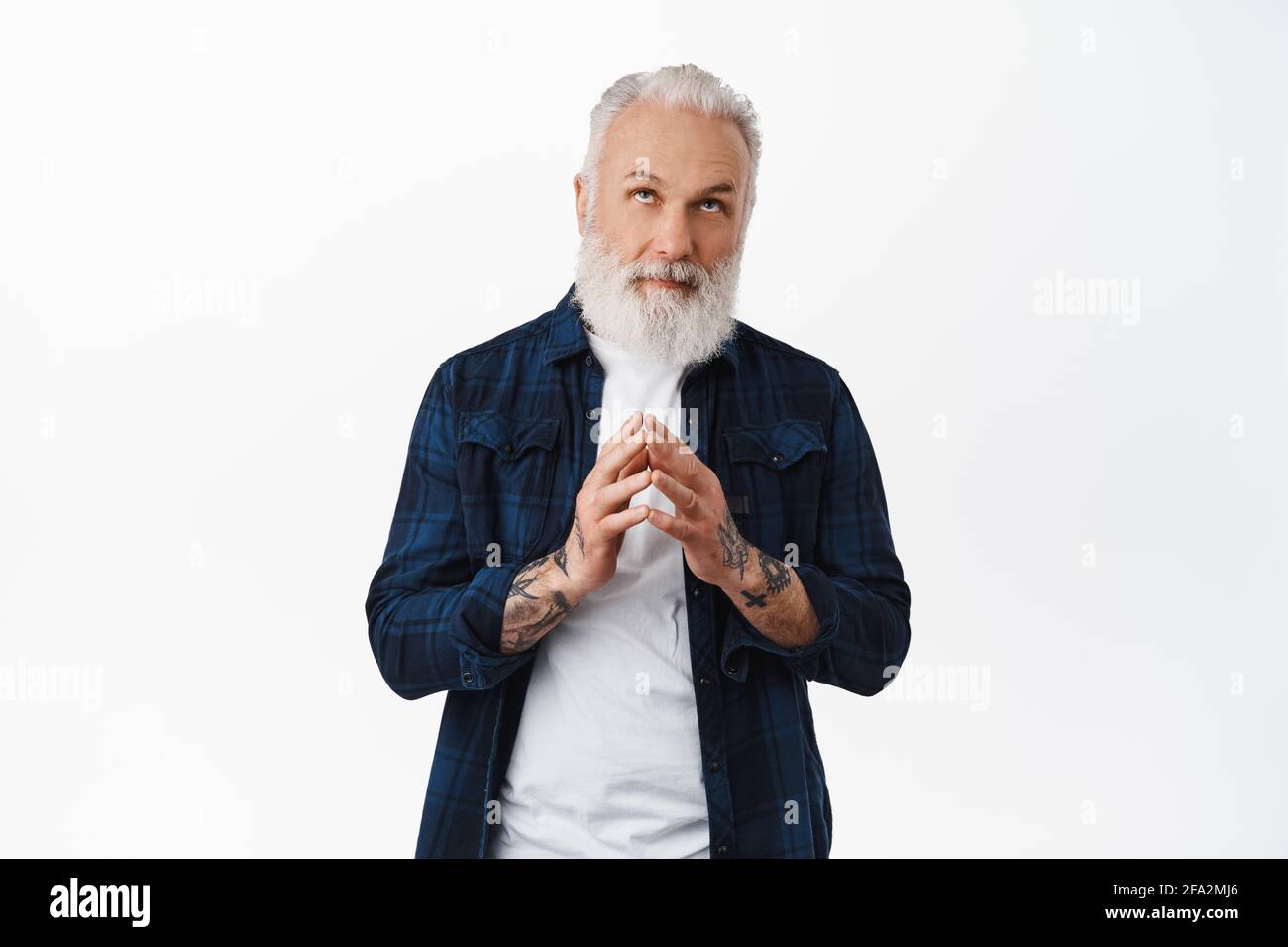 Thoughful old stylish man steeple fingers, looking up and thinking, making plan, scheming like evil genius while reading promotional text above head Stock Photo