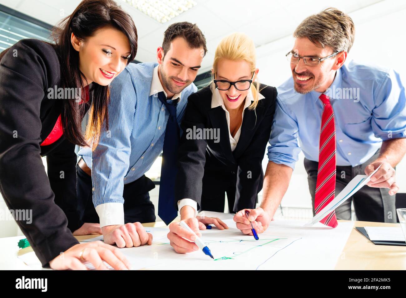 Four professionals in office in business attire having strategy meeting to determine the future of company Stock Photo