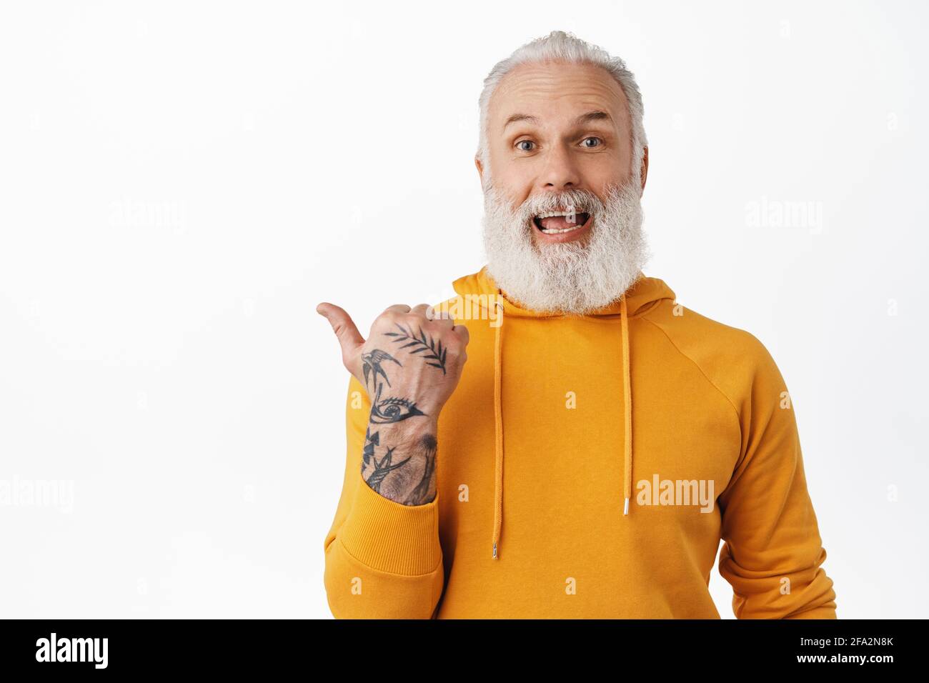 Excited happy old man with tattoos laughing, pointing left and showing  something cool, amazed by advertisement promo deal, standing in stylish  hoodie Stock Photo - Alamy