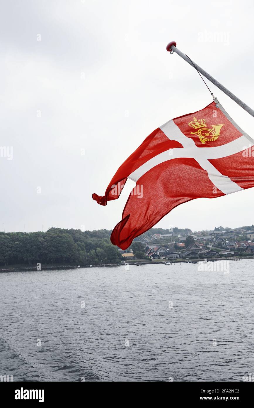 Svendborg, Denmark - August 14, 2018. A ferry with a large Danish flag arrives at the port of Svendborg. Stock Photo