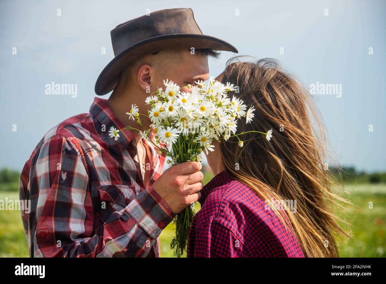 couple in love of man and woman kissing behind daisy bouquet in