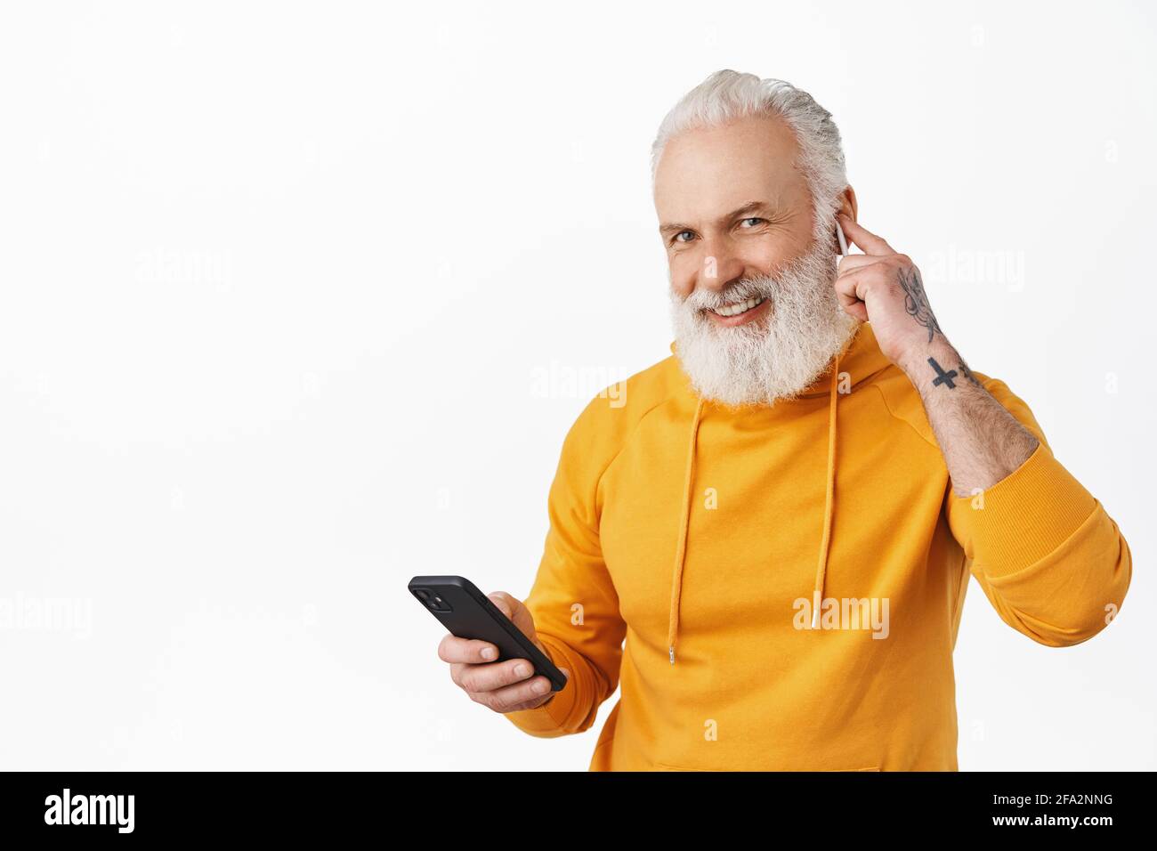 Grandfather listen music on wireless earphones, put headphone in ear