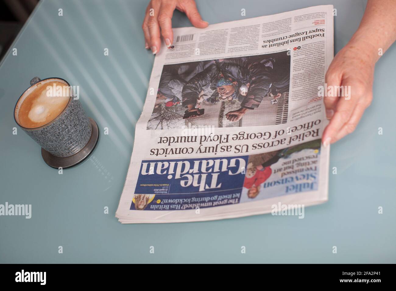 The Guardian, British Daily newspaper being read on glass table with coffee Stock Photo