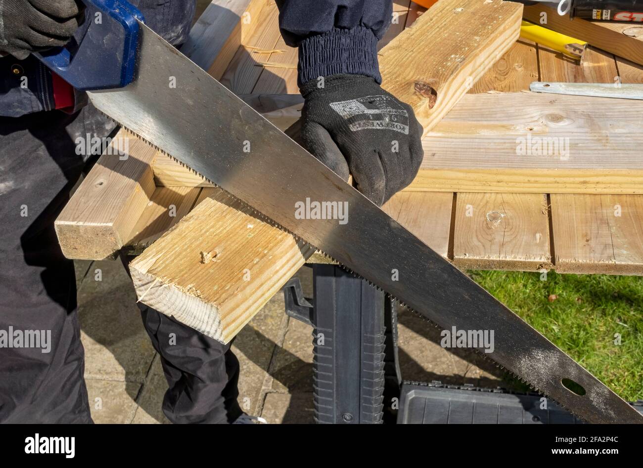Close up of man joiner person sawing using handsaw to cut piece of wood England UK United Kingdom GB Great Britain Stock Photo