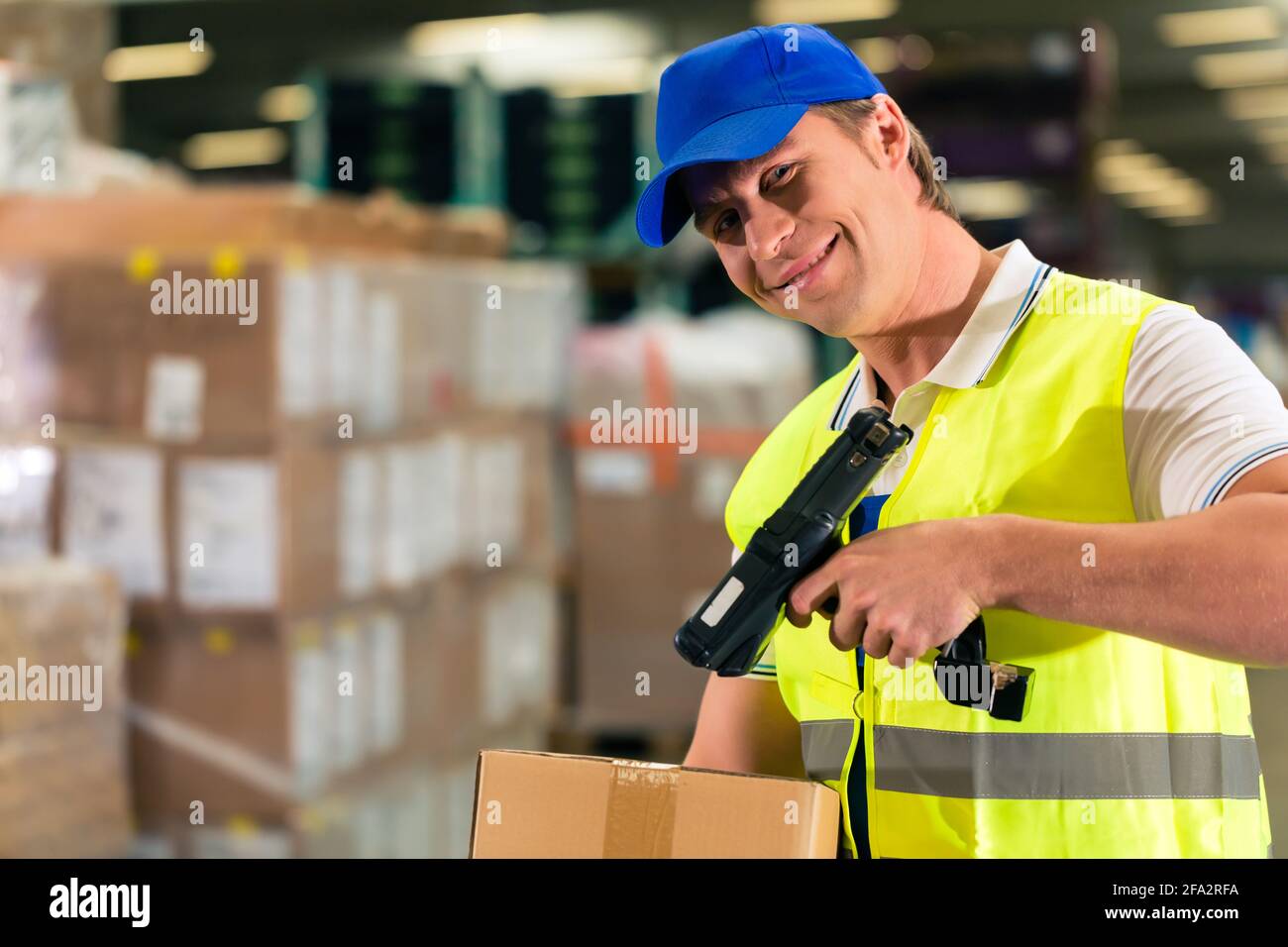 Warehouseman with protective vest and scanner, scans bar-code of ...