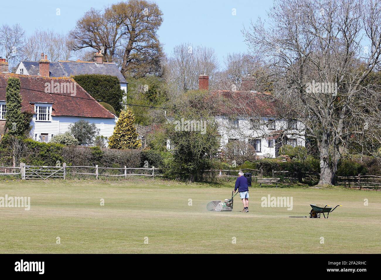 Newenden, Kent, UK. 22 Apr, 2021. UK Weather: Sunny in the small village of Newenden in the district of Ashford, Kent. A groundsman mows the village grounds cricket playing field on a warm and sunny spring day. Photo Credit: Paul Lawrenson /Alamy Live News Stock Photo