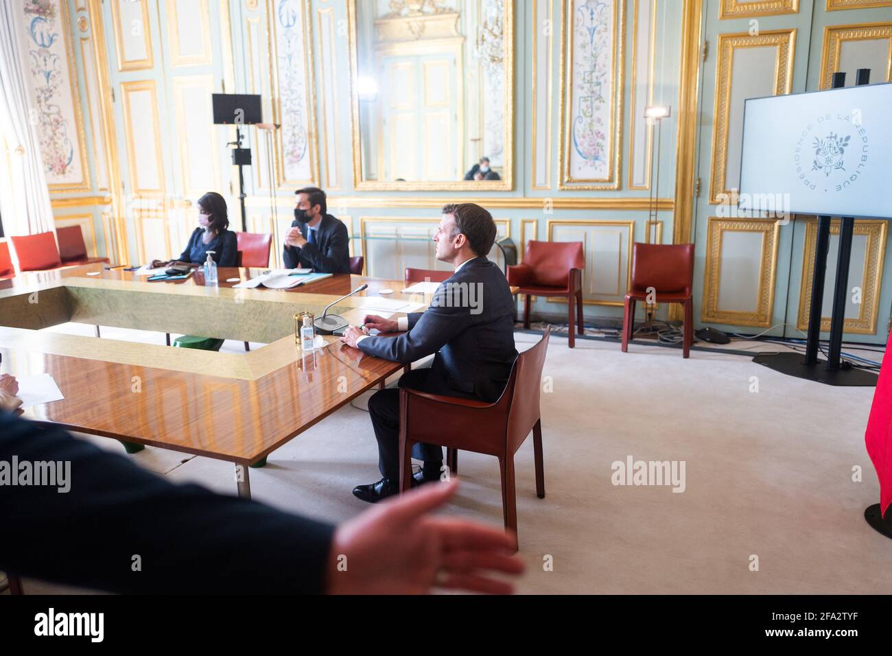 French President Emmanuel Macron listens to US President Joe Biden (on screen) speak during a virtual Earth Day Climate Summit, video conference call, at the Elysee Palace in Paris on April 22, 2021. President Joe Biden on April 22, 2021, sharply ramped up US ambitions on slashing greenhouse gas emissions, leading new pledges by allies at a summit he hopes brings the world closer to limiting climate change. Biden told a virtual Earth Day summit that the world's largest economy will cut emissions blamed for climate change by 50 to 52 percent by 2030 compared with 2005 levels. Photo by Romain Ga Stock Photo