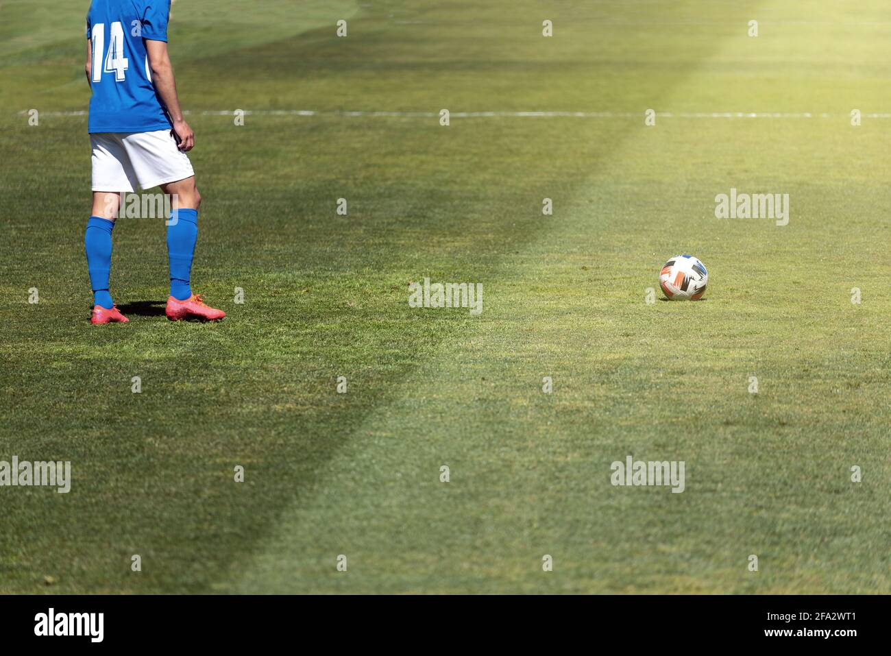Soccer player ready to take a free kick a few meters away from the ball on a natural grass pitch. Stock Photo
