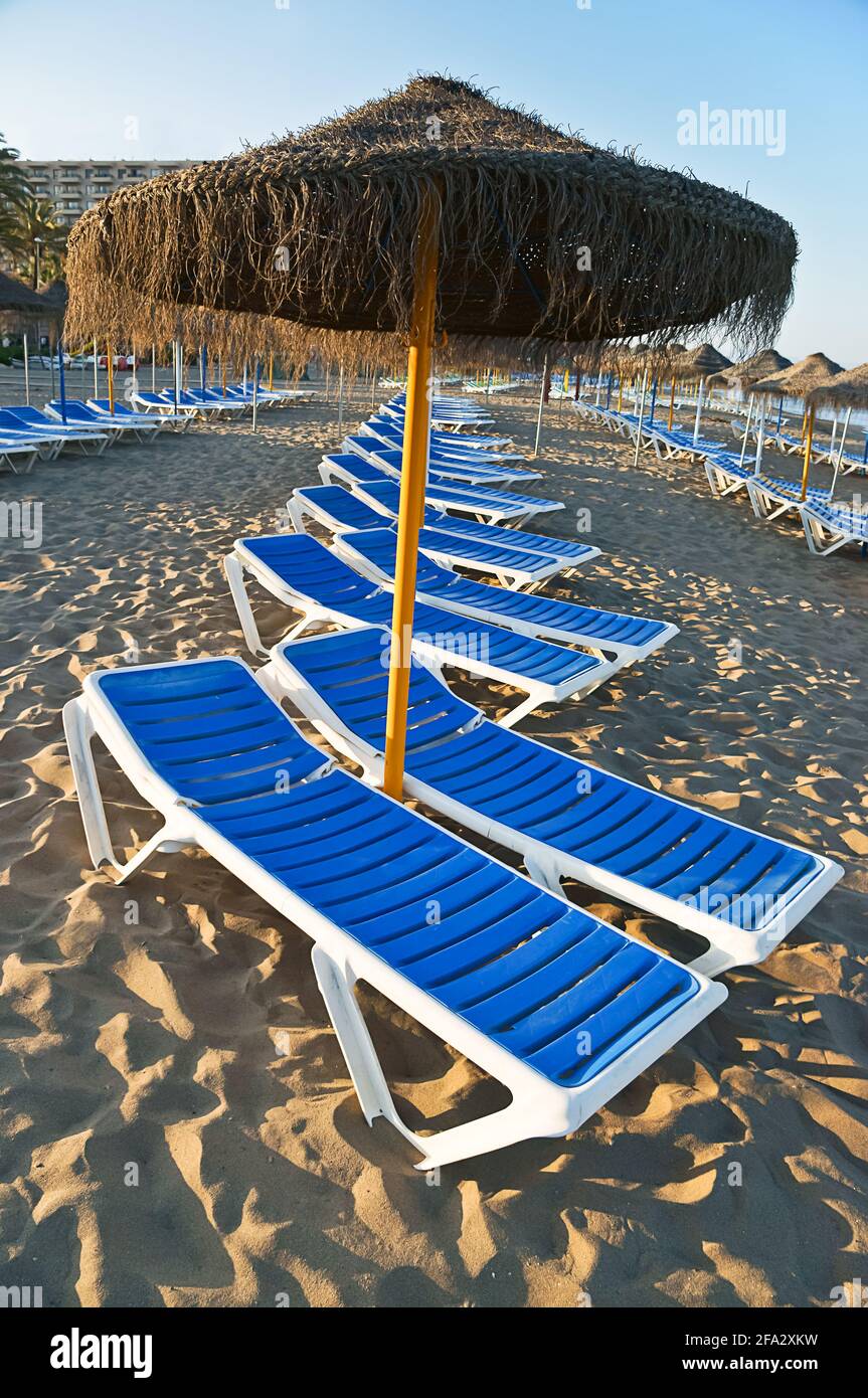 Vertical shot of a straw umbrella and sun loungers on a beach in  Torremolinos, Malaga, Spain Stock Photo - Alamy