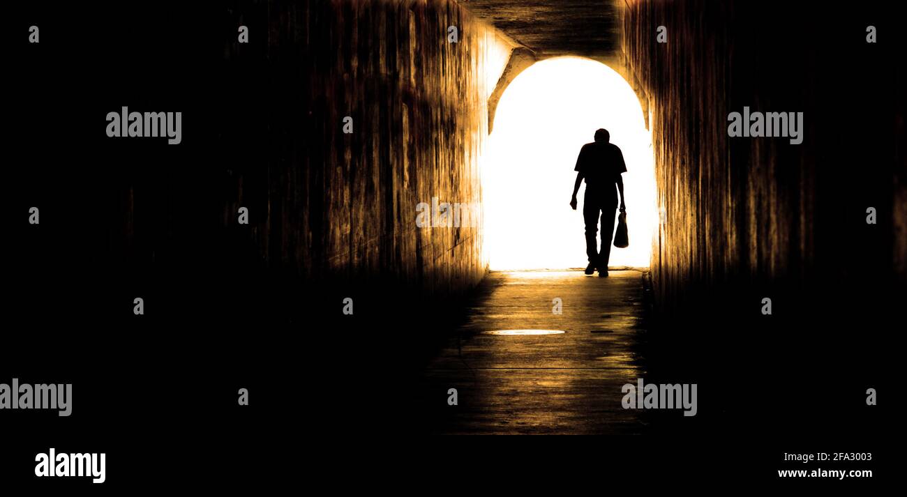 Old man walking through tunnel sihouetted Stock Photo