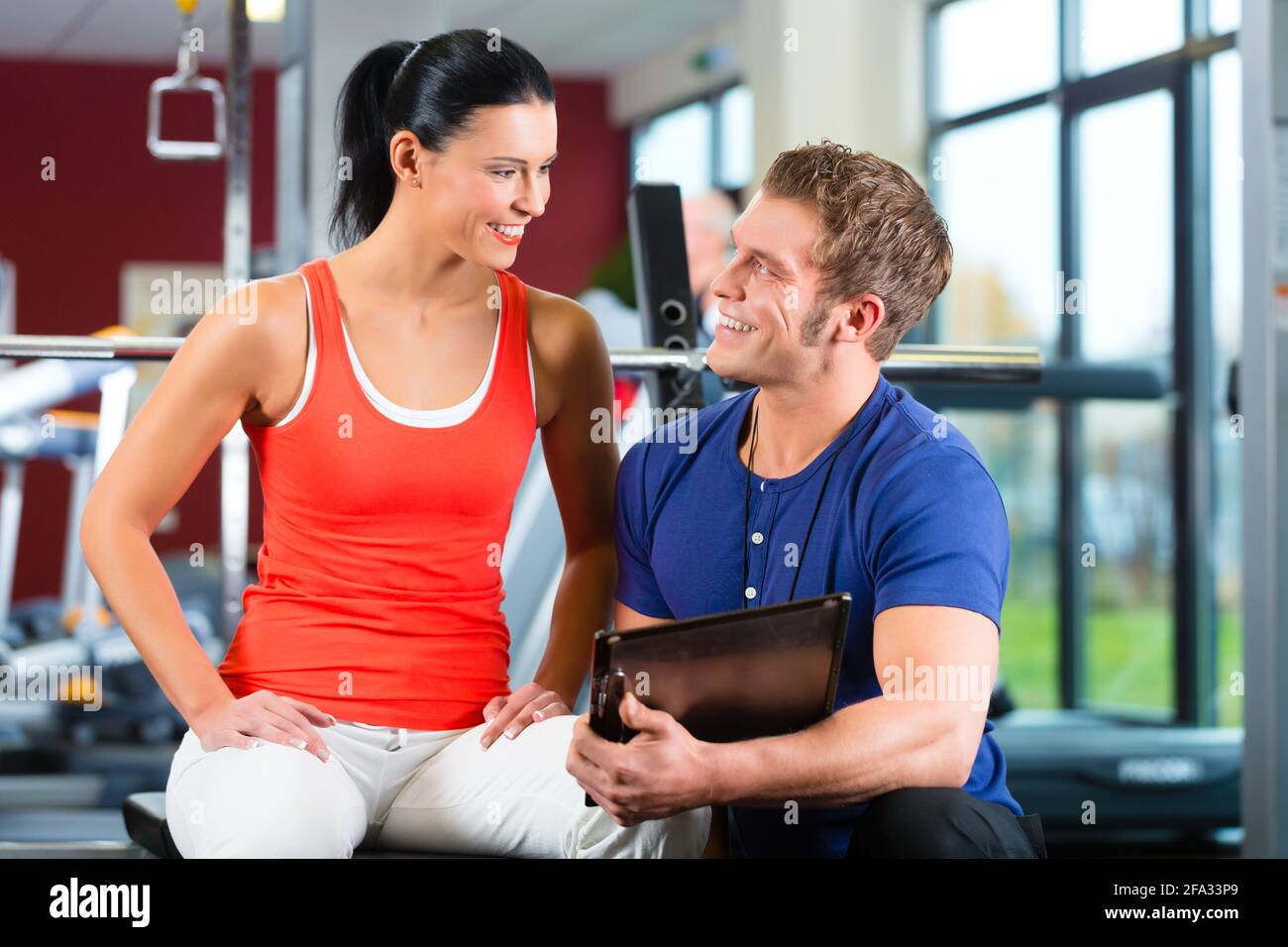 Woman with her personal fitness trainer in the gym Stock Photo - Alamy