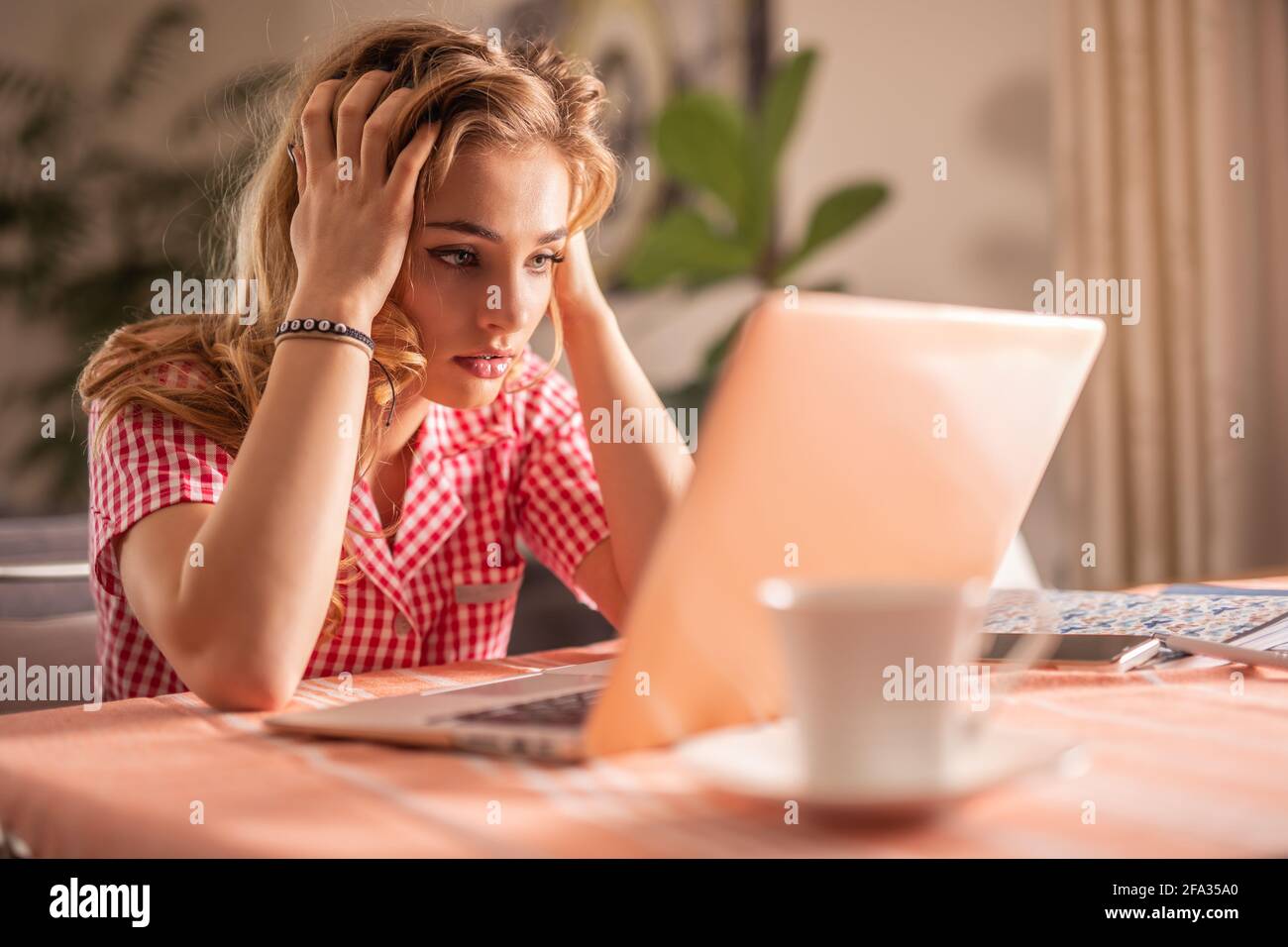 Angry exhausted woman holding her head during online call with unreliable employees. Stock Photo