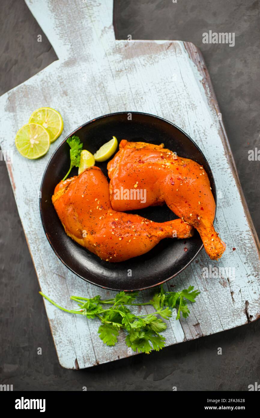 Marinated chicken leg without skin arranged in a black plate and