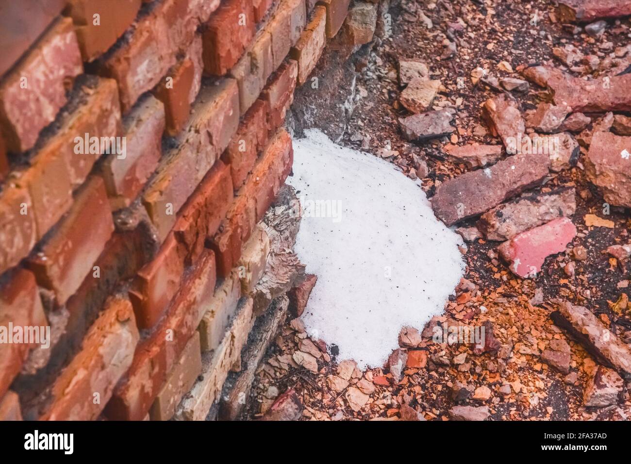 White ammonia saltpeter, fertilizer woke up through the destroyed old brick wall of the industrial warehouse with fertilizer. Stock Photo