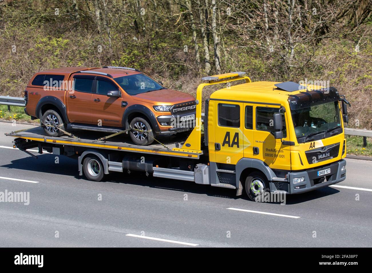 AA, roadside assistance for 2918 Ford Ranger Wildtrak 4x4 Tdci,  transporting, commercial, driven, symbol, automobile, way, moving, british, road transport, traffic, drive, driver, AA, breakdown recovery, low loader, British roads, MAN vehicles, driving, vehicle, car, motorway, uk, england, isolated, passenger, passengers, freeway, city, speed, street, in motion, urban, modern, background, traveling, movement, landscape, truck, AA van, highway, traffic lanes, 24hr emergency roadside recovery, double cab, towing equipment,  24/7 Stock Photo