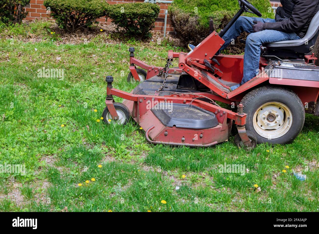 Utility worker in lawn mower gardener cutting the grass ride-on lawnmower Stock Photo