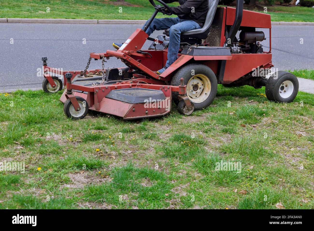 Lawn mower cutting green grass in gardening backyard Stock Photo