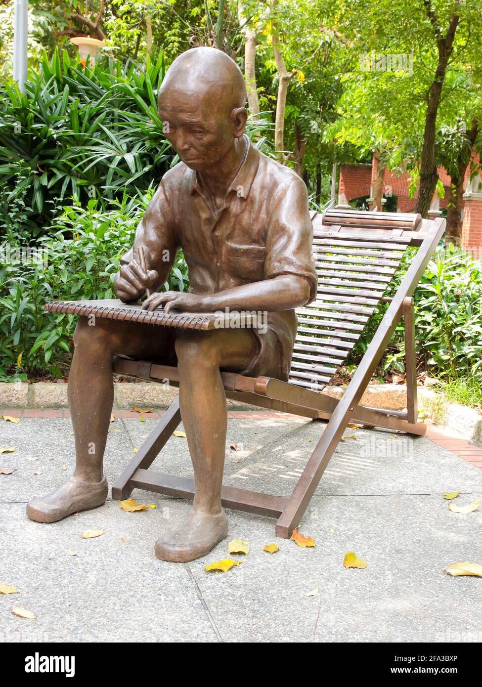 A nice bronze sculpture of a peasant old man sitting on a folding chair, drawing on a pad. In Taipei, Taiwan. Stock Photo