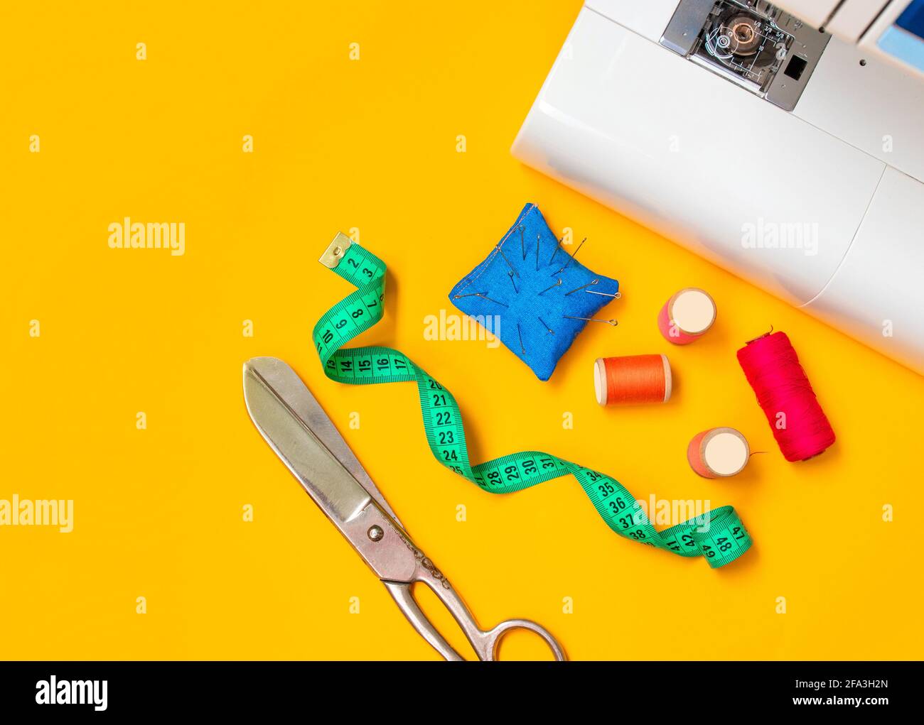 Sewing accessories. Composition with threads and sewing accessories on yellow background. Workplace of seamstress.Top view, copy space, flat lay Stock Photo