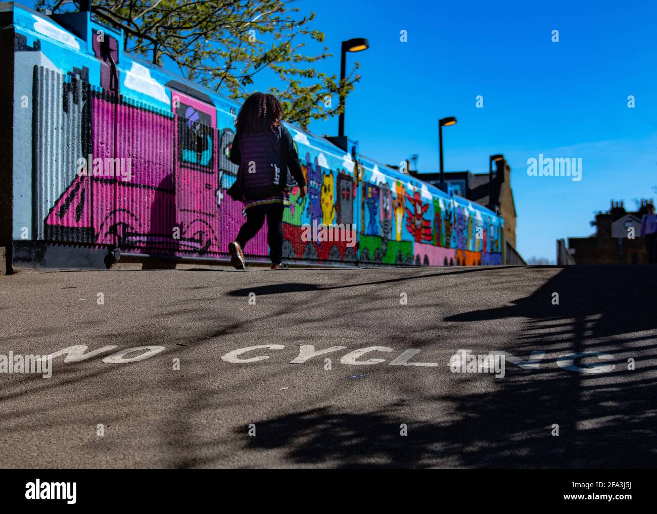 Woman crossing a graffiti railway bridge in Hampstead, London, UK Stock Photo