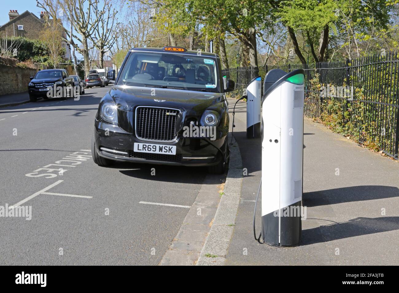 Kerbside electric vehicle charging points on Elmwood Rd in Dulwich, London, UK. Shows new LEVC TX plug-in hybrid electric taxi connected and charging. Stock Photo