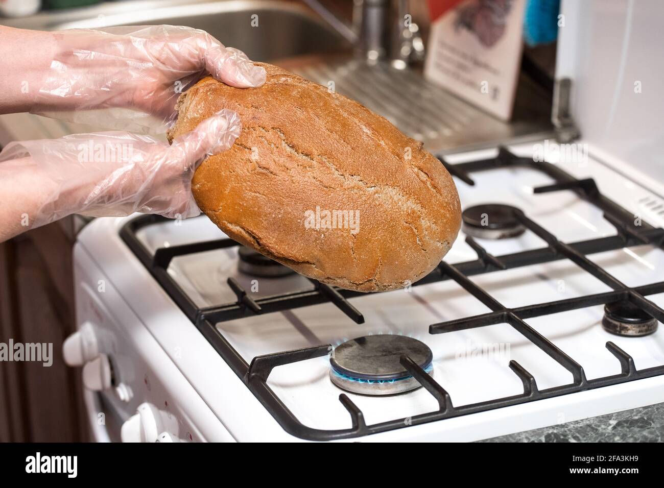 Woman hand in plastic bag hold bread over a gas stove, fighting different types of bacteria and