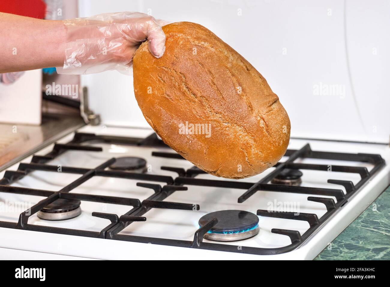Woman hand in plastic bag hold bread over a gas stove, fighting different types of bacteria and