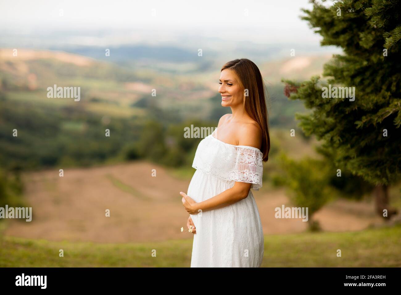 Young pregnant woman in white dress at the summer field Stock Photo - Alamy