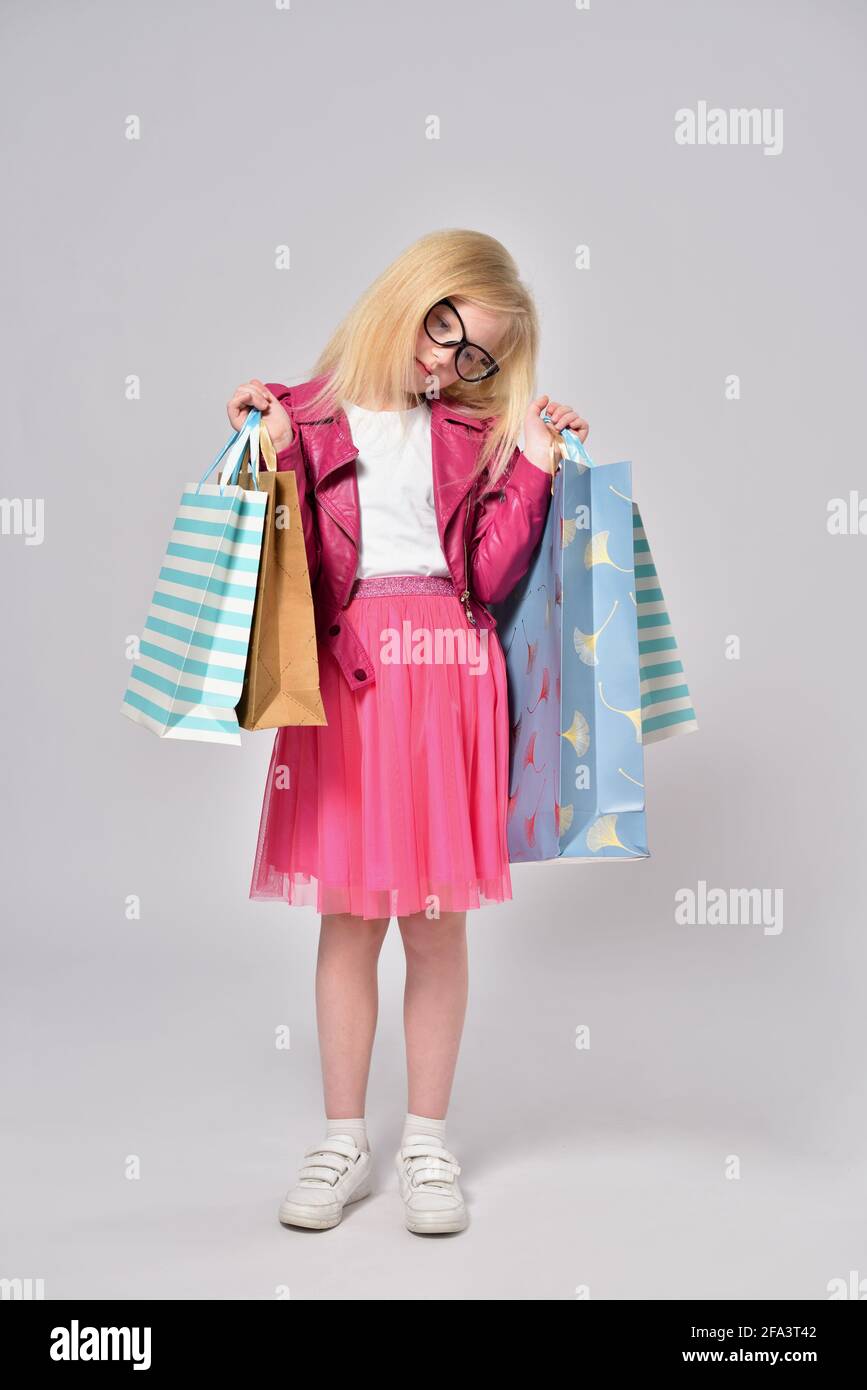 Child girl holding heavy shopping bags and tired of shopping Stock