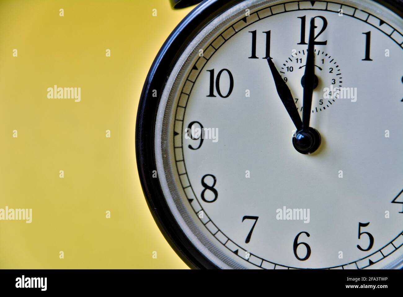 Shot of vintage retro analog clock on yellow background showing 11 o