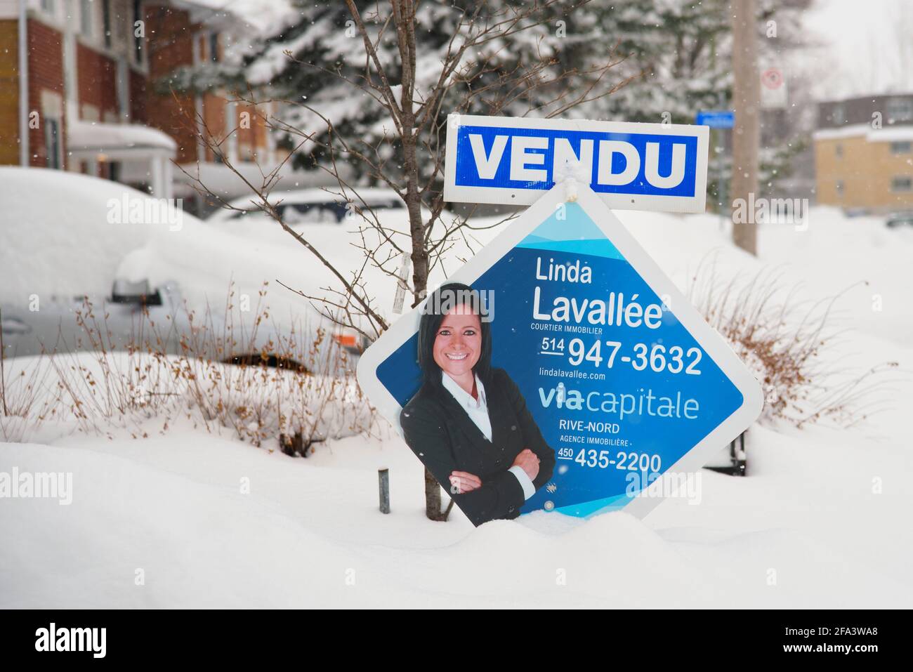 House for sale 'sold' sign in French, with a picture of the realestate agent. Laval, province of Quebec, Canada. Stock Photo