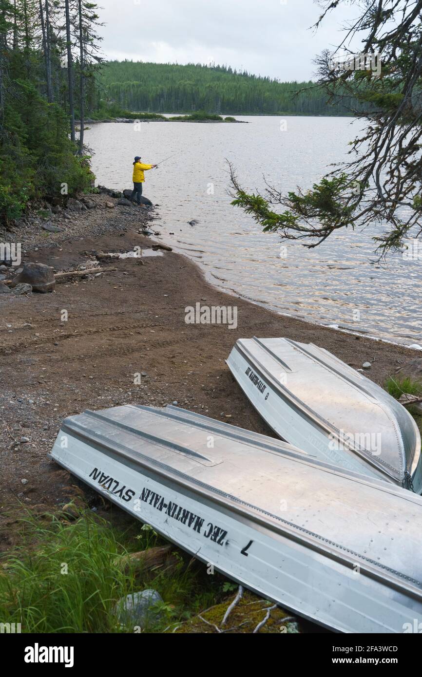 Fisherman casting his line from  the shore of a lake in the Monts Valin region, province of Quebec, Canada. Stock Photo