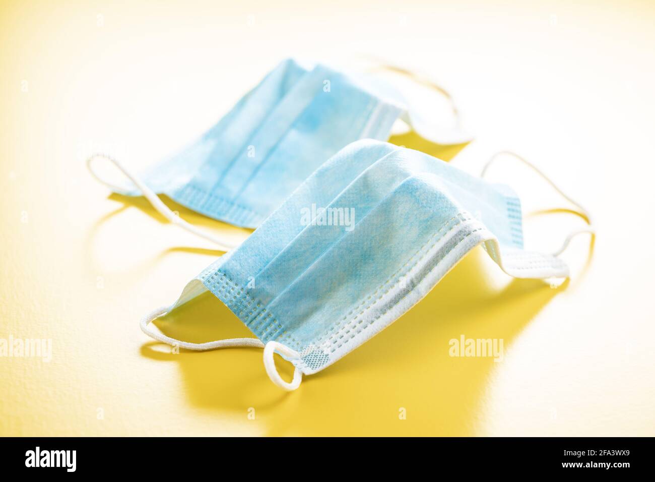 Surgical face mask. Coronavirus protection. Covid-19 protection mask on yellow background. Stock Photo