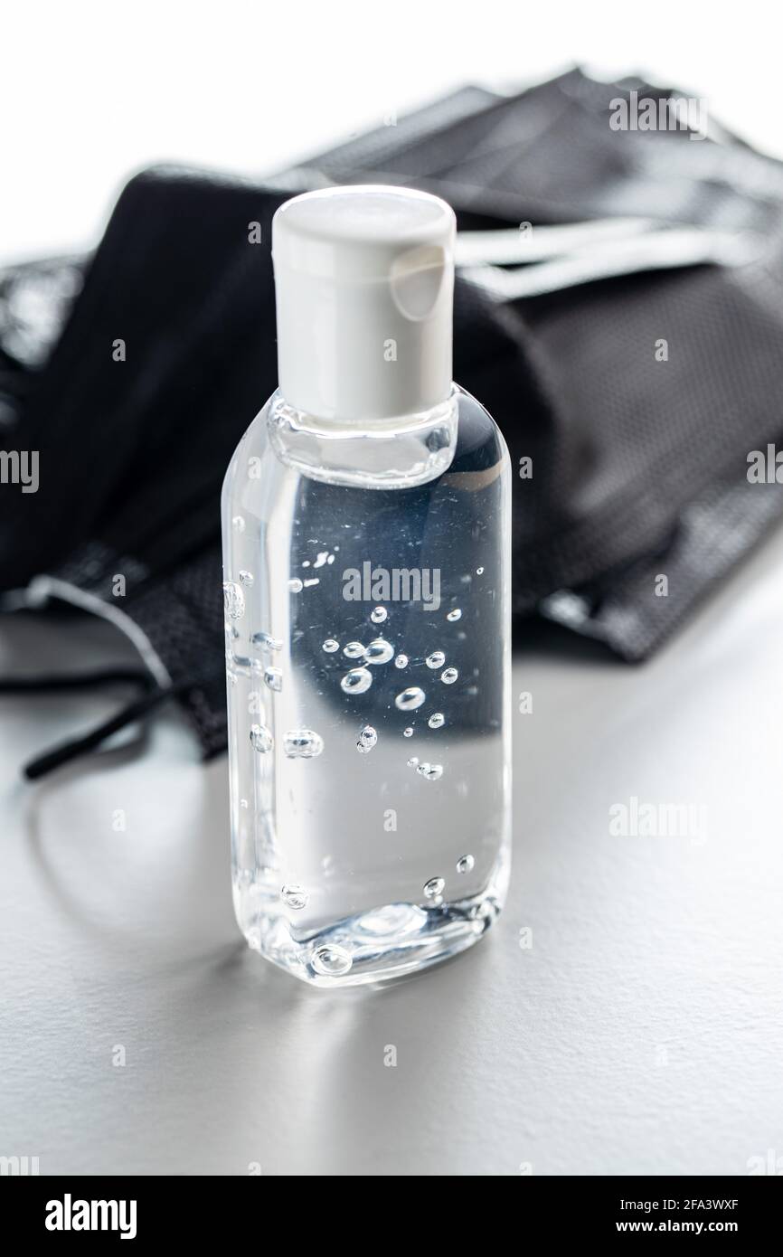 Coronavirus prevention hand sanitizer gel in bottle. Hand disinfectant gel and surgical face mask on grey background. Stock Photo