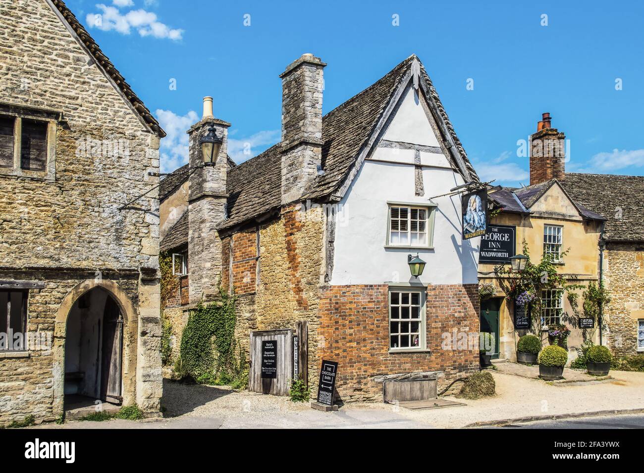 July 25 2019 Lacock UK - Street scene and alley in Cotswold village of Lacock where scenes from Downton Abbey were shot - the George Inn- Wadworth Stock Photo
