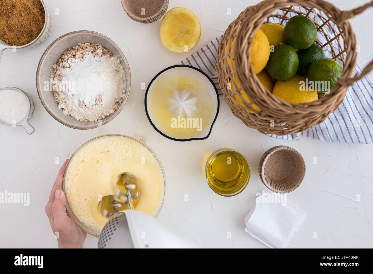 Woman hand beating some eggs with a blender in a bowl over a white