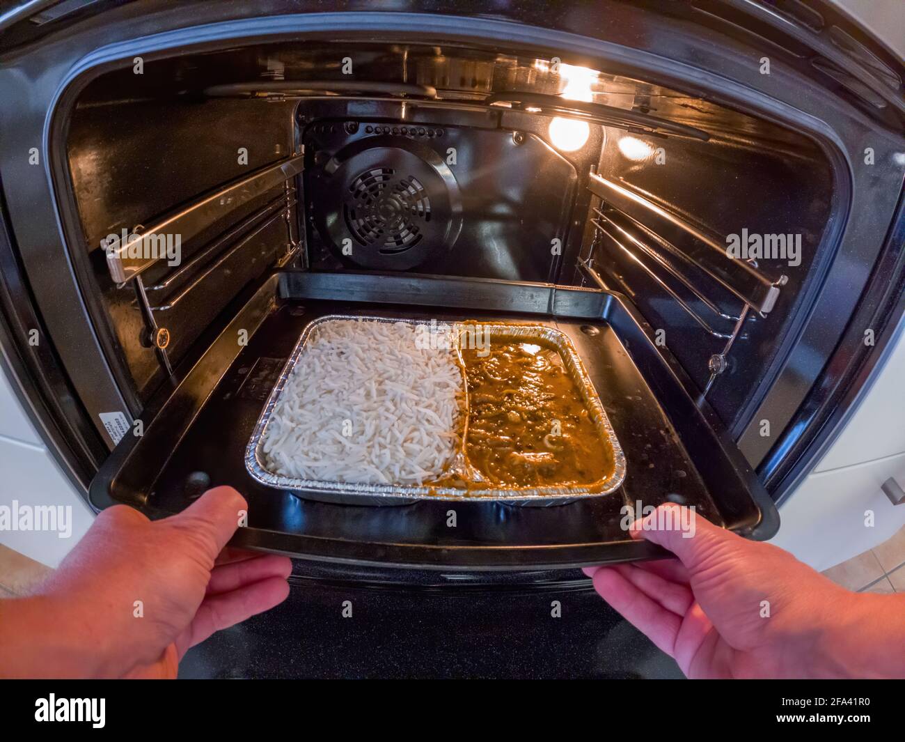 Hands putting take away meal in the oven Stock Photo